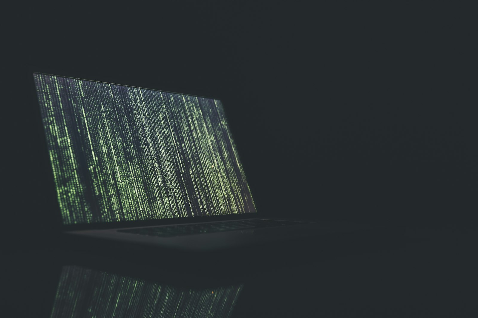 Laptop screen filled with streams of code in a dark room